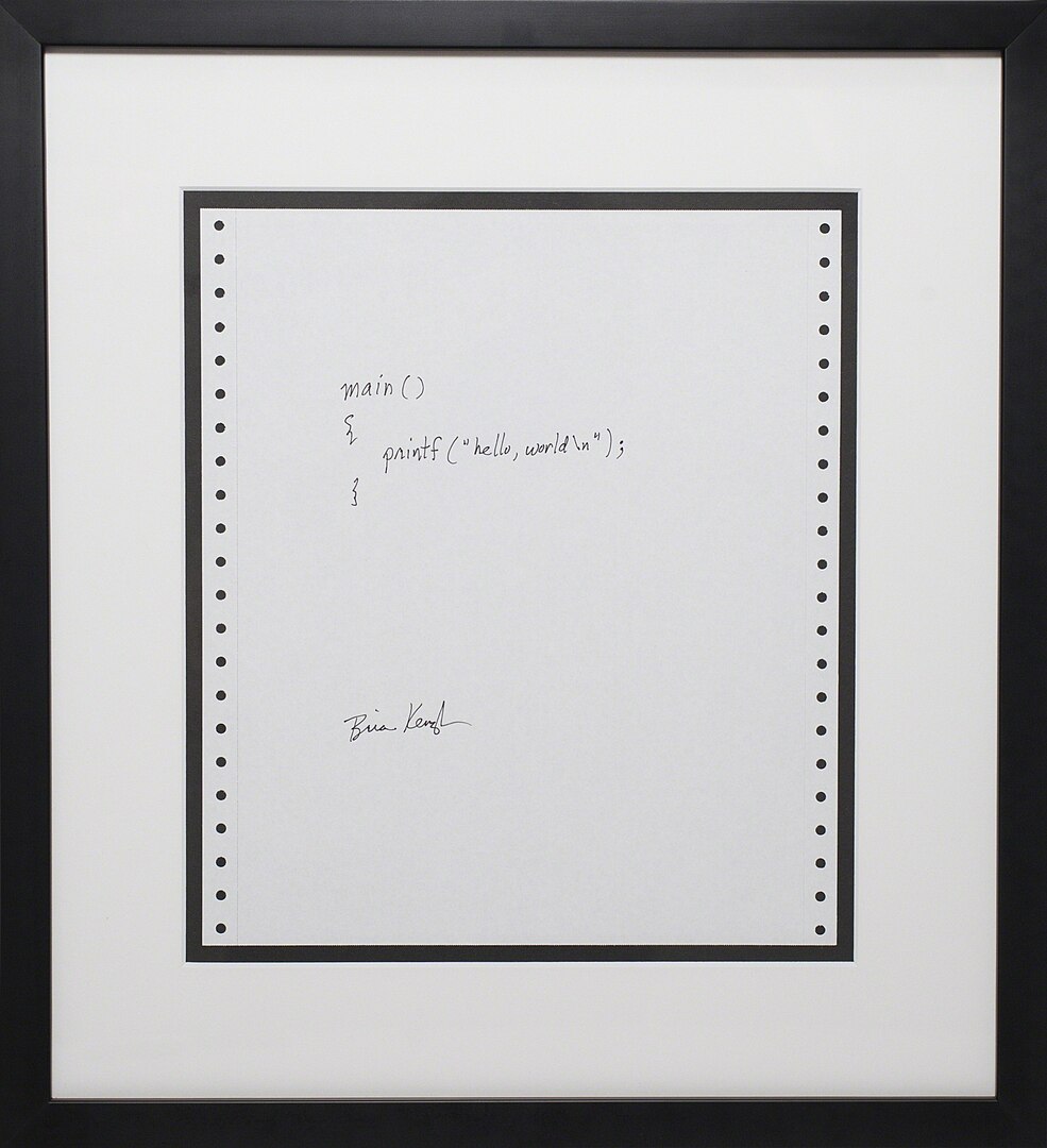 A picture of a paper signed by Brian Kernighan with his famous program 'hello, world'